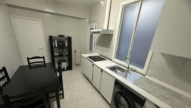 Une cuisine de taille réduite équipée d’un lave-linge, d’un four à micro-ondes et d’un évier.