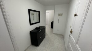 Un couloir avec une commode noire, un miroir et une porte dotée d’une poignée en laiton.