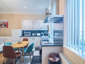 A modern kitchen with a dining area, featuring a wooden table, chairs, and a microwave. - Creative & Cheerful Apartment by Avo in Sheffield (Sheffield)