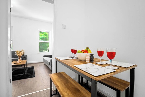 A modern dining area with a wooden table, marble placemats, and a bowl of fruit.