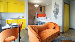 A modern hotel room with a bright yellow kitchen, a cozy orange sofa, and a bed with a wooden headboard. - Sheffield City Escape - Modern Apartment (Sheffield)