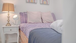 A bedroom with a bed, a bedside table with a lamp, a mirror, and two wall art pieces. - Chic and Cheerful pad in Sheffield City (Sheffield)