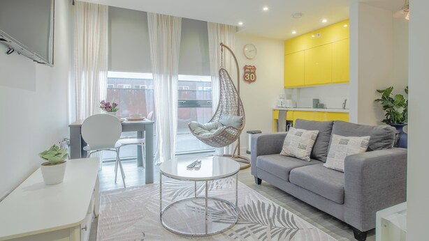 A modern living room with a grey sofa, a hanging chair, a round coffee table, and a small dining table. - Chic and Cheerful pad in Sheffield City (Sheffield)