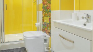 A bathroom with a shower, toilet, sink, and a colorful floral tile design. - Chic and Cheerful pad in Sheffield City (Sheffield)