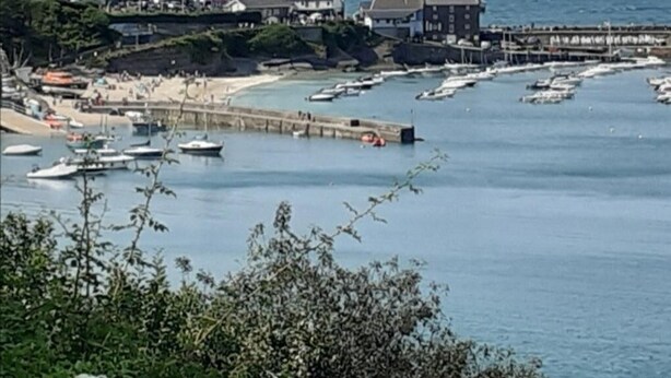 Una località balneare con un molo, barche e edifici lungo la costa.