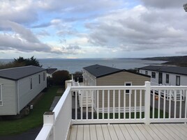 A view of a waterfront property with multiple mobile homes, a deck, and a grassy area.
