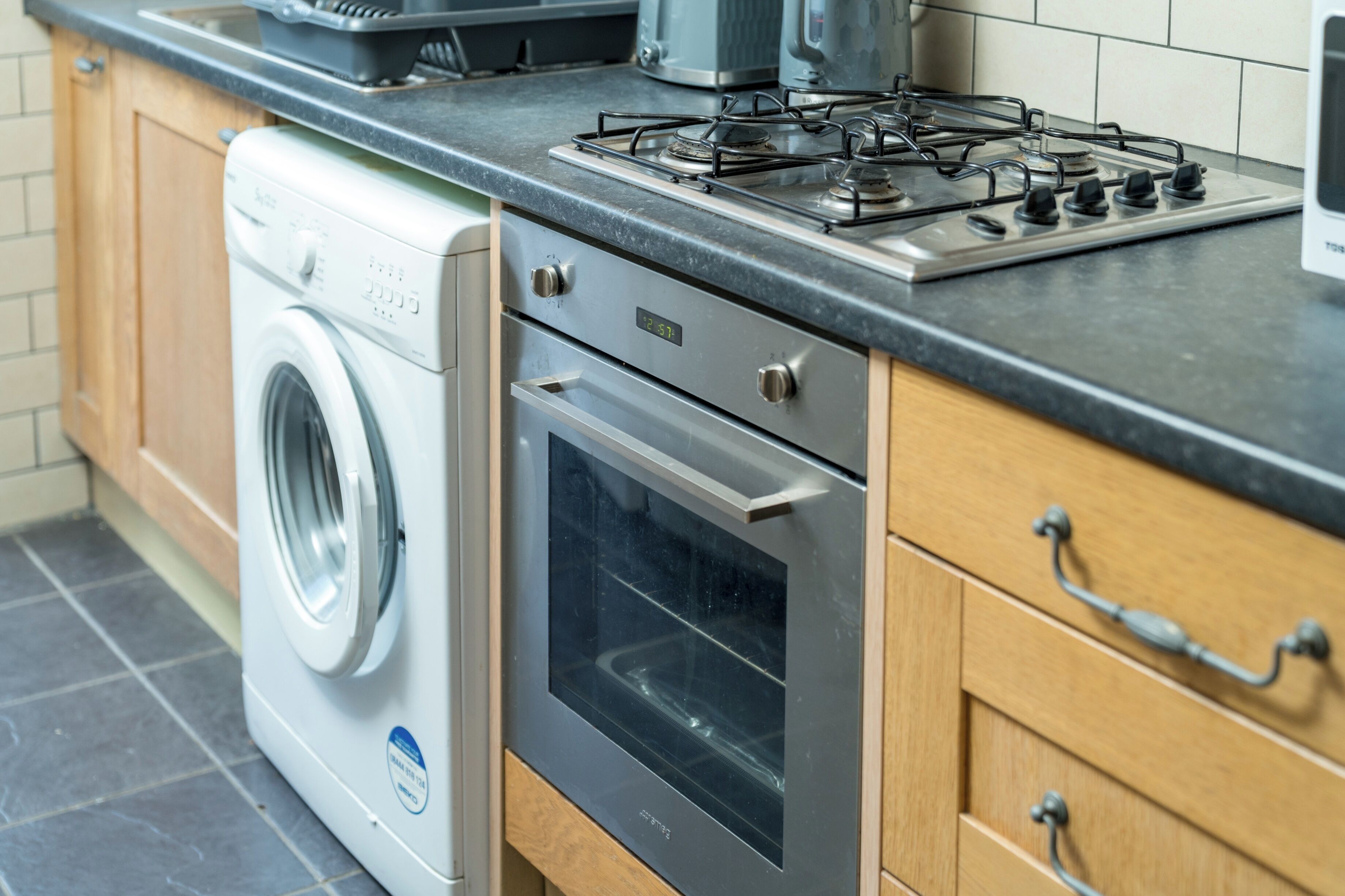 A kitchen with a built-in washer, oven, and gas stove.