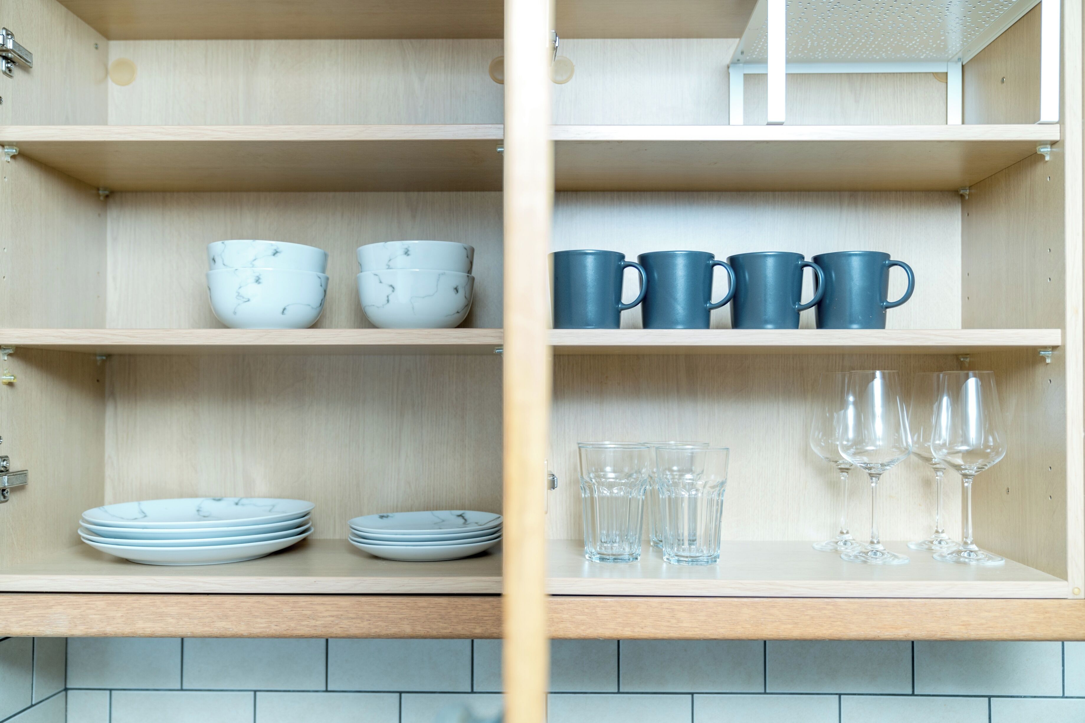 A kitchen with wooden shelves holding plates, bowls, cups, and glasses.