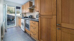 A kitchen with wooden cabinets, a washing machine, and a stove. - Crawley Stainer 1-bedroom With Parking and Garden (Crawley)