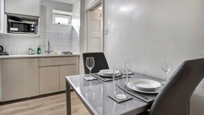 A modern kitchen with a microwave, sink, and cabinets. There is a dining table set with plates, glasses, and cutlery. - 3 Bed Home w/ 2 Bathrooms &free Parking Sleeps 6 (London)