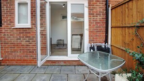 A brick house with a glass door leading to a room. There is a table outside the door. - 3 Bed Home w/ 2 Bathrooms &free Parking Sleeps 6 (London)