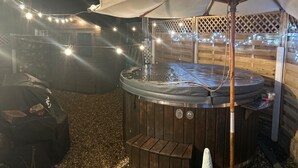 A hot tub with an umbrella, surrounded by wooden fencing and string lights. - Luxury Seymour House With Spa, Gym & Lake District (Morecambe)
