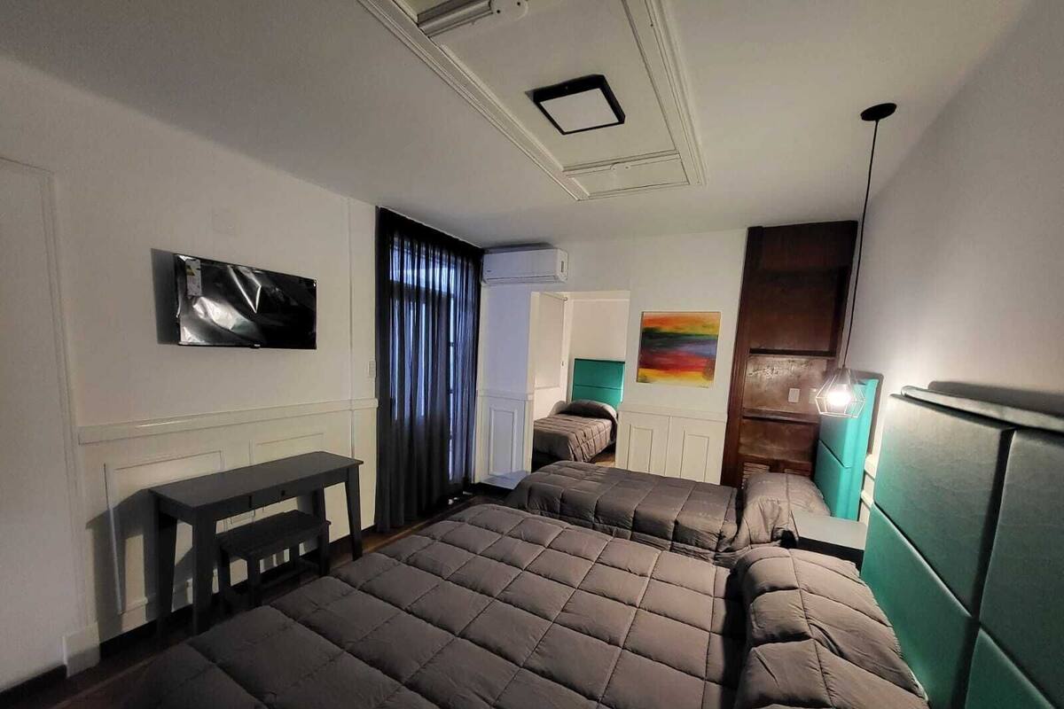 A hotel room with two beds, a TV, a desk, and a painting on the wall.