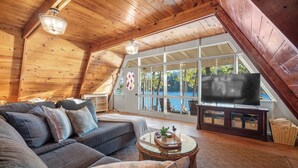 Un dormitorio estilo loft acogedor con un ventanal grande, televisión y una zona de estar cómoda.