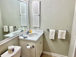 A bathroom with a toilet, sink, mirror, towel rack, and a bottle of hand soap. - La Vie Insulaire -optional BIKES–Walk 2 Redfern Village, shops, and restaurants! (St. Simons Island)