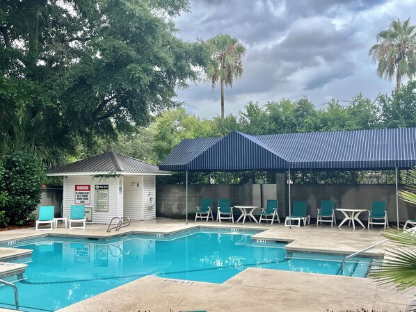 A swimming pool with lounge chairs and a covered seating area. - La Vie Insulaire -optional BIKES–Walk 2 Redfern Village, shops, and restaurants! (St. Simons Island)
