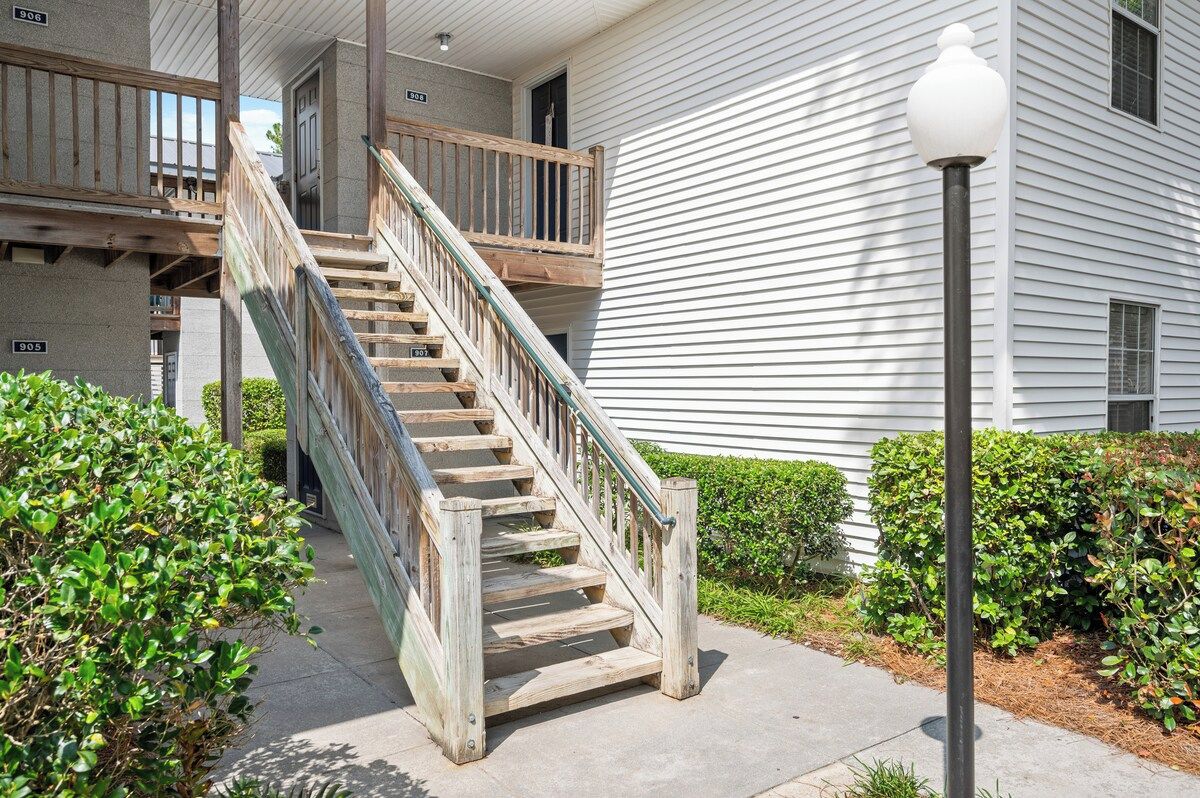 A wooden staircase leading to a building with white siding and a black lamp post.