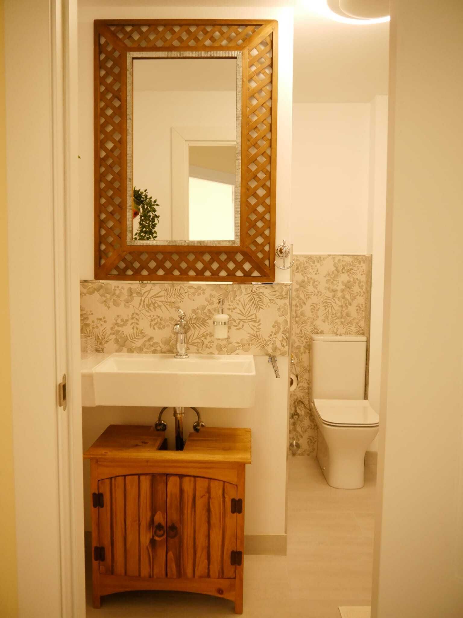 A bathroom with a wooden cabinet, a sink, a mirror, and a toilet.