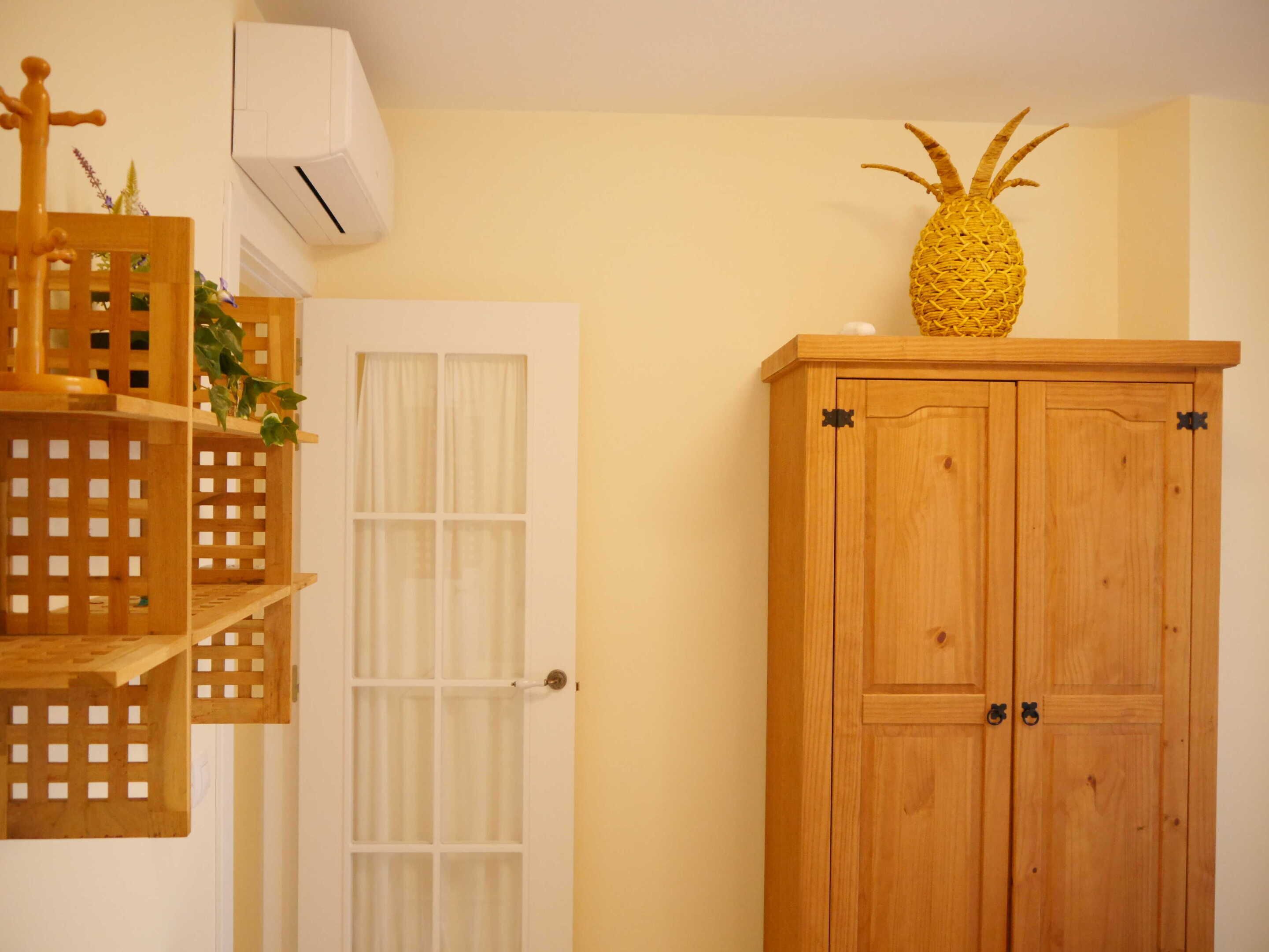 A room with a wooden cabinet, a white door, and a shelf with a pineapple decoration.