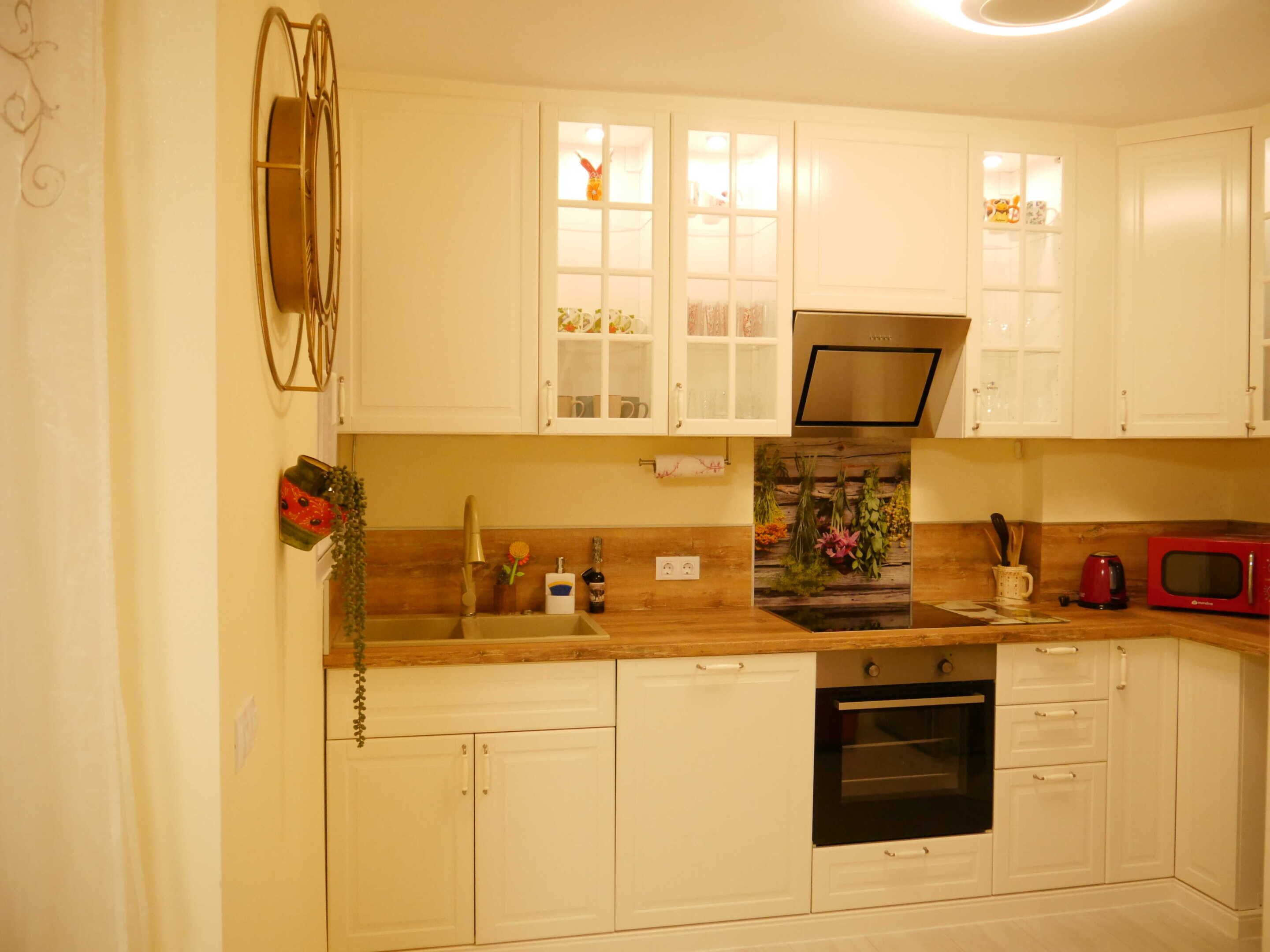 A compact kitchen with white cabinets, a microwave, an oven, and a sink.