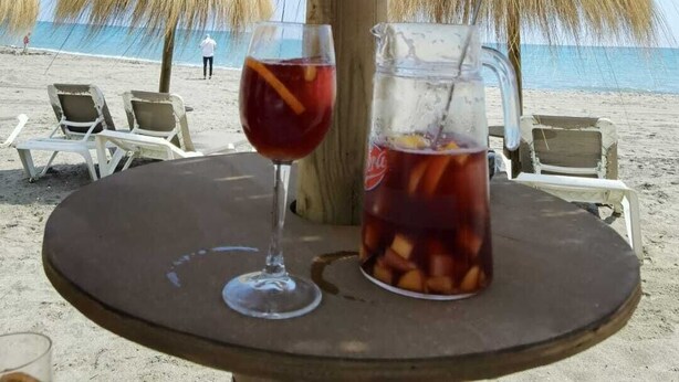 A beach umbrella with a drink and a pitcher on a table. - Guadiana Sol (Estepona)