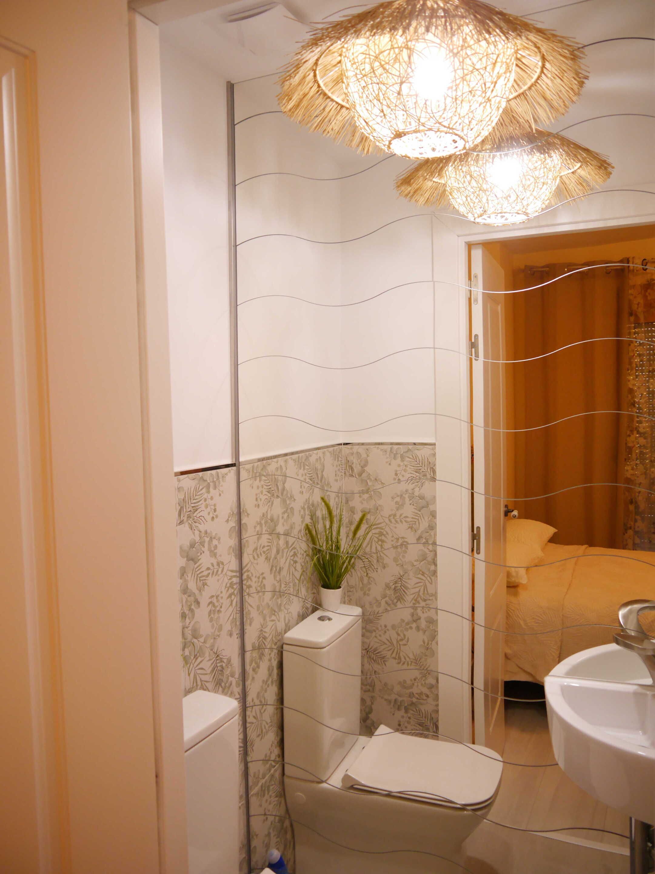 Un bagno con il water, un lavandino e una pianta decorativa.