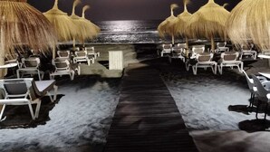 A beachside walkway with thatched umbrellas and lounge chairs, leading to the ocean. - Guadiana Sol (Estepona)