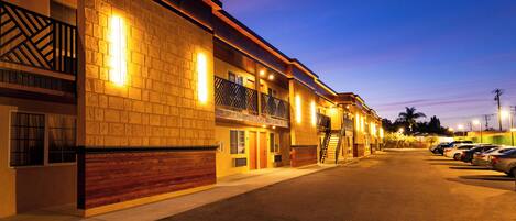 A hotel with a brick facade, multiple balconies, and a parking lot.