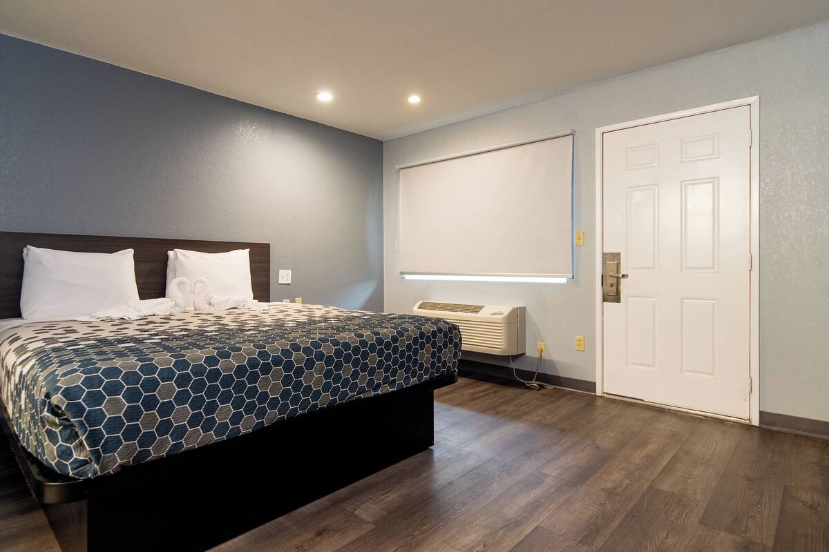 A bedroom with a bed, a wall-mounted air conditioner, and a door.
