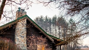 A rustic log cabin with a stone chimney, surrounded by a stone pathway and a small garden. - Inground Pool, Hot Tub, Fire Pit at Large Log Cabin near Mohican State Park (Butler)