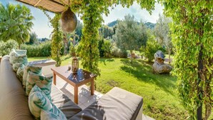 A covered outdoor seating area with a sofa and table, surrounded by greenery and a view of the landscape. - Spacious Villa With Infinity Pool (Son Servera)