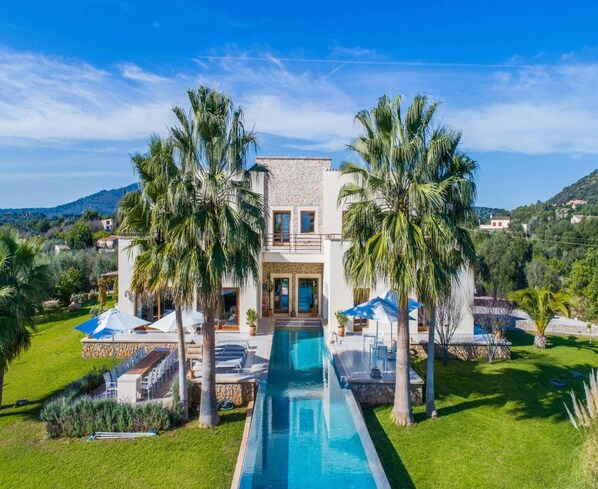 A two-story house with a swimming pool in the center, surrounded by palm trees and a well-maintained lawn. - Spacious Villa With Infinity Pool (Son Servera)