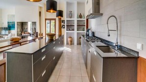 A modern kitchen with a central island, black pendant lights, and a stainless steel sink. - Spacious Villa With Infinity Pool (Son Servera)