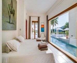 A hotel room with a bed, a view of a swimming pool, and a painting on the wall. - Spacious Villa With Infinity Pool (Son Servera)