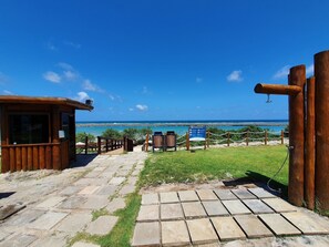 A wooden structure with a view of the ocean, a stone pathway, and a sign with text.