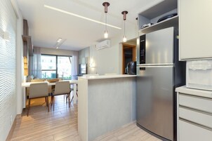 A modern kitchen with a built-in refrigerator, a dining area with a table and chairs, and pendant lighting.