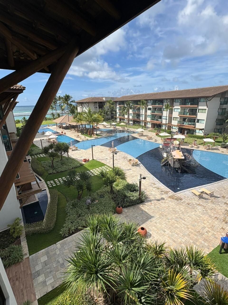 Un resort con múltiples piscinas, palmeras y vista al océano.