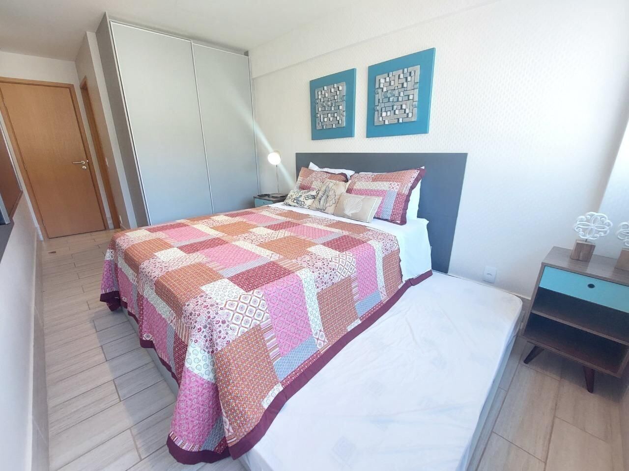 Une chambre à coucher comprenant un lit, une table de chevet, une armoire et deux œuvres d’art murales.