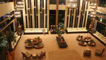 Um hall amplo com diversas áreas de estar, uma mesa de centro e plantas decorativas.