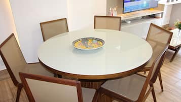 Una mesa redonda de comedor con un plato decorativo, rodeada de sillas de madera.