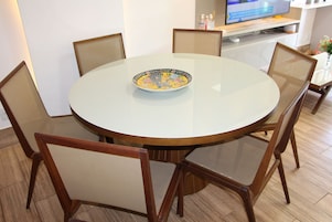 A round dining table with a decorative plate, surrounded by wooden chairs.
