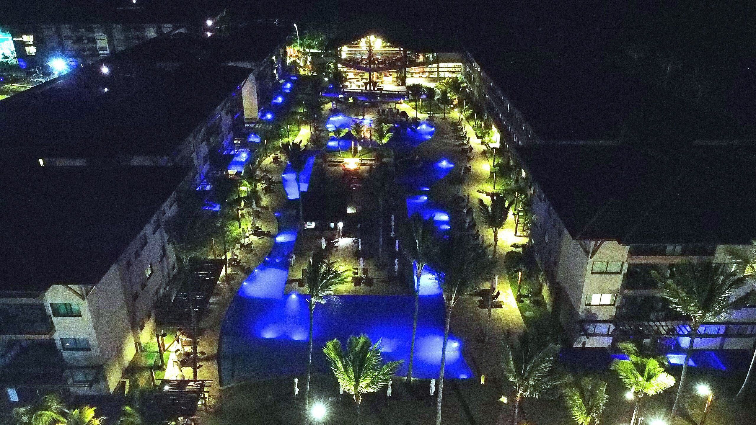A hotel with a pool area, outdoor seating, and a covered section.