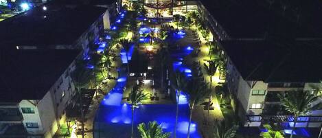 A hotel with a pool area, outdoor seating, and a covered section.