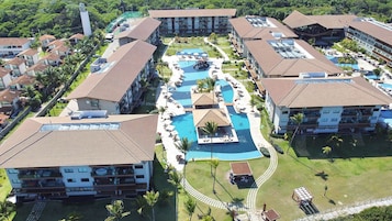 A resort with multiple buildings, a central swimming pool, and surrounding greenery.