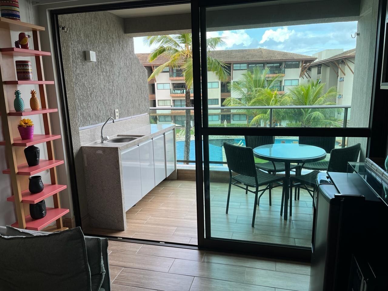A modern kitchen with a view of a pool and a balcony with outdoor furniture.