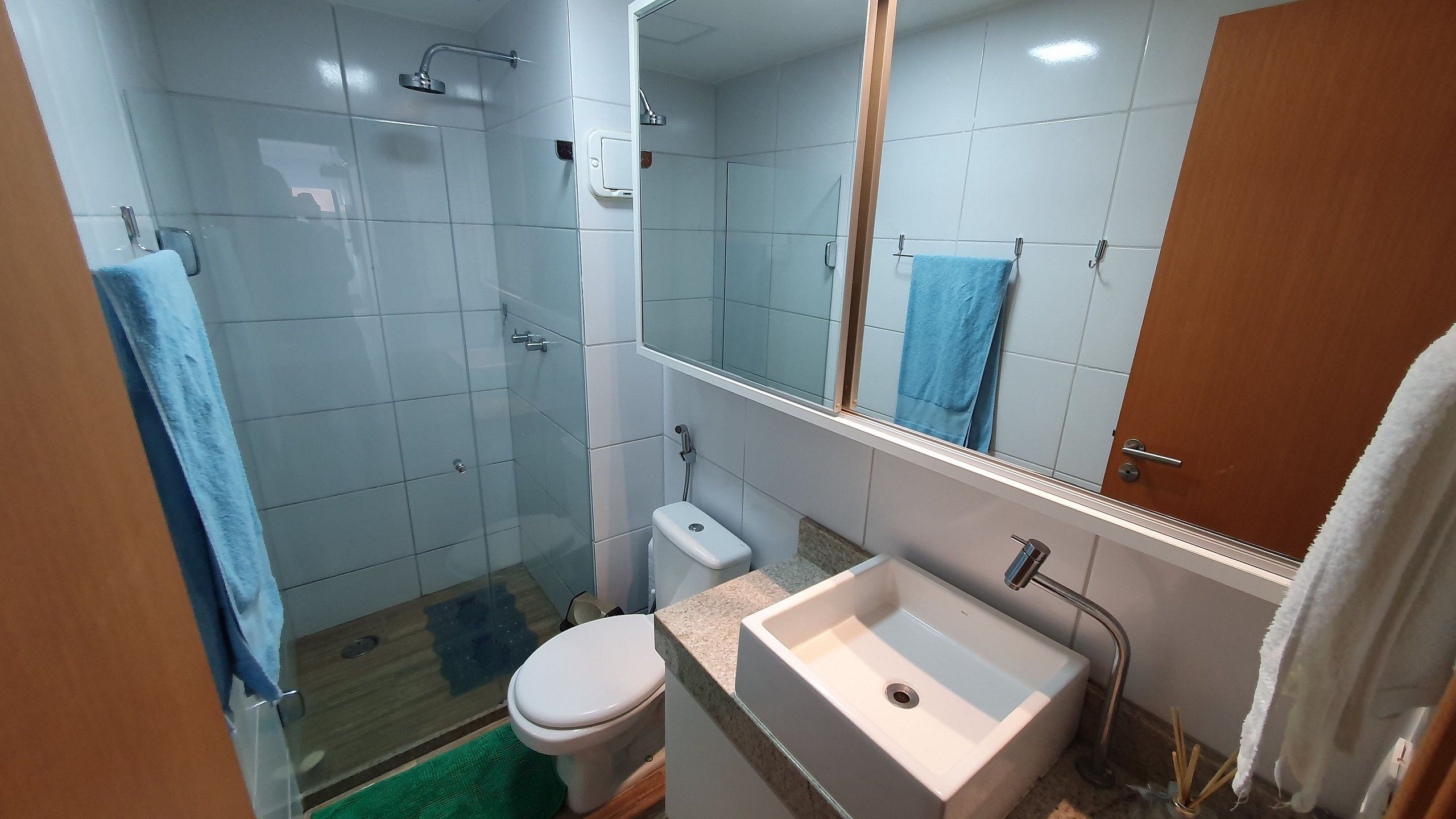 A bathroom with a shower, toilet, sink, and a mirror.