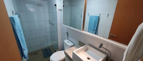 A bathroom with a shower, toilet, sink, and a mirror.