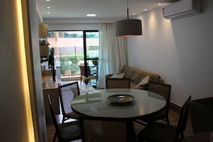 A dining area with a round table, chairs, a sofa, and a view of the outdoors.