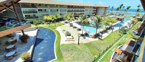 Un resort con múltiples piscinas, mobiliario exterior y vista al océano.