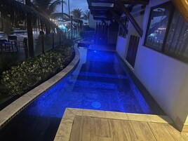 A pool with blue lighting, a wooden deck, and a covered walkway.